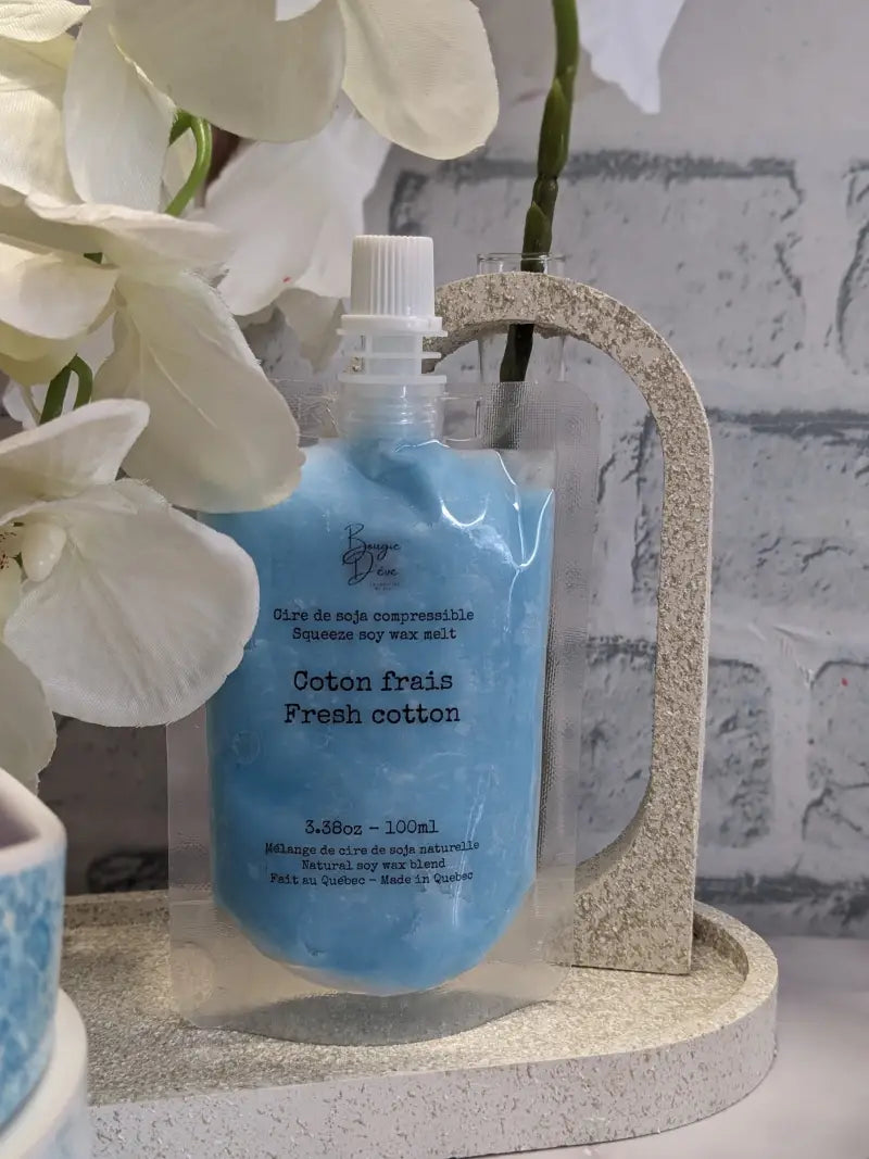 une bouteille de liquide bleu à côté d’une fleur blanche