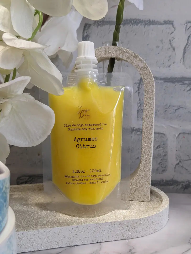 une bouteille de liquide jaune à côté d’une fleur blanche