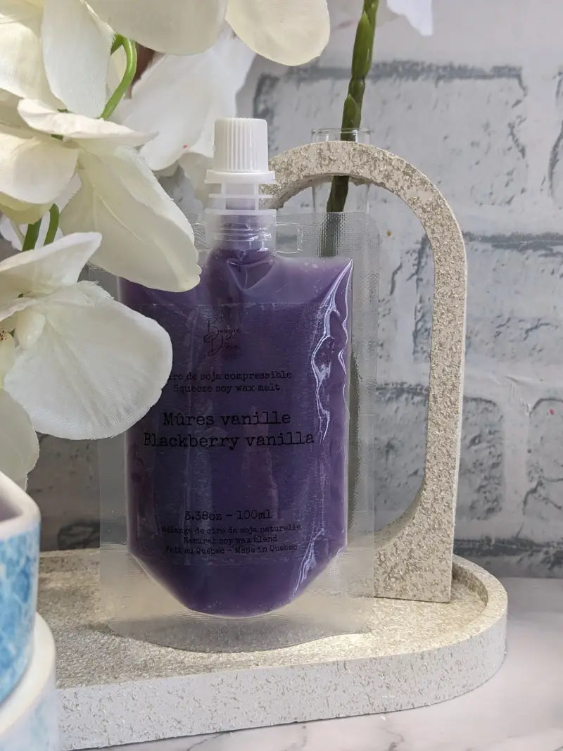 une bouteille de liquide lavande à côté d’une fleur blanche