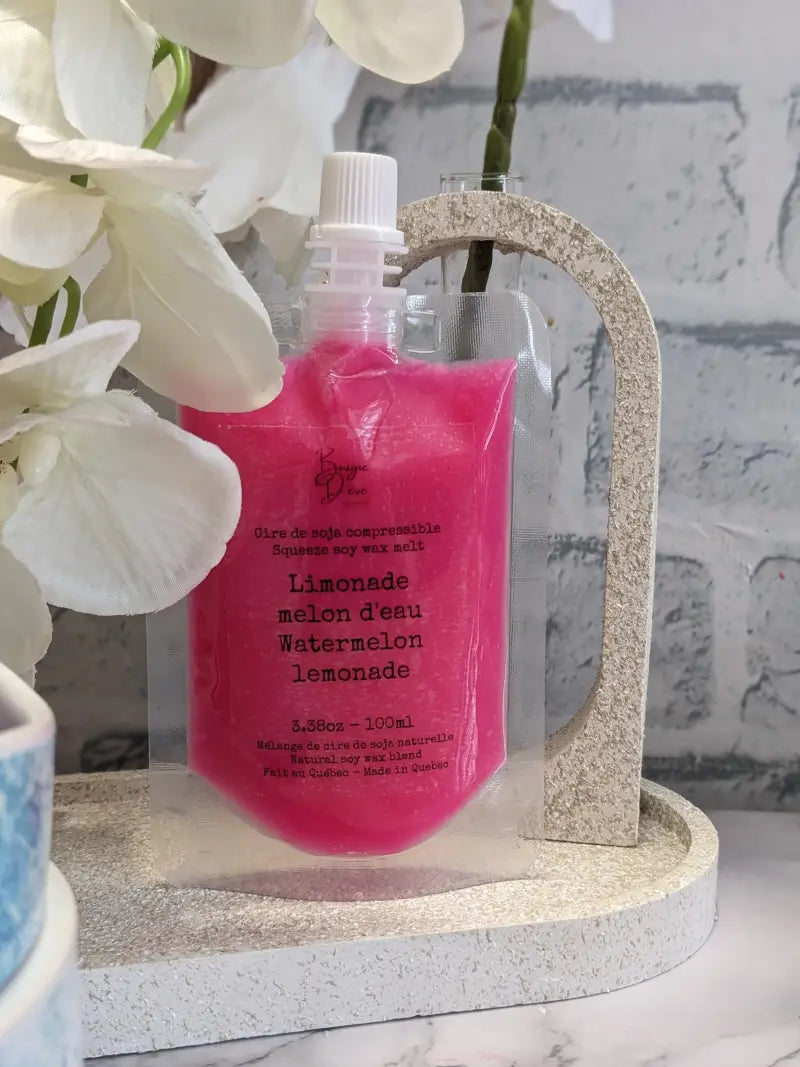 une bouteille de liquide rose posée sur un plateau de marbre