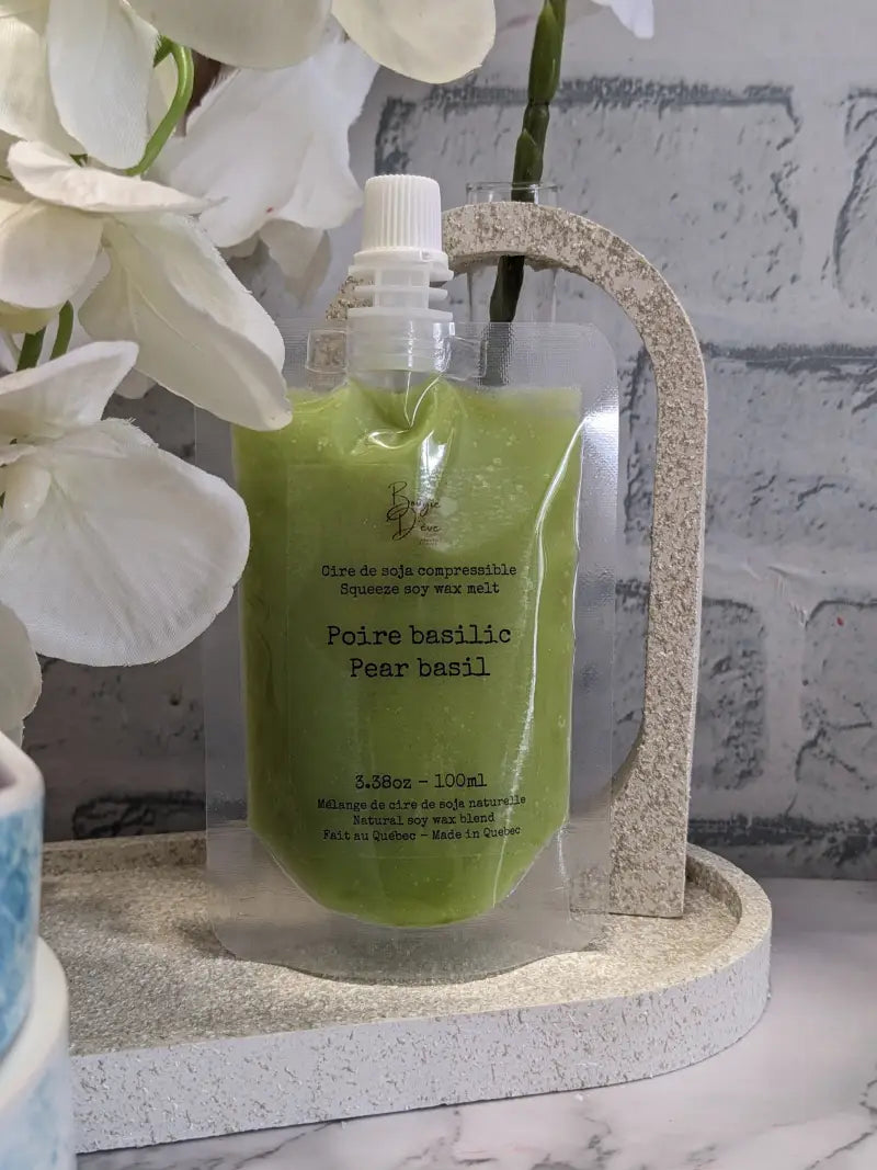 une bouteille de liquide vert à côté d’une fleur blanche